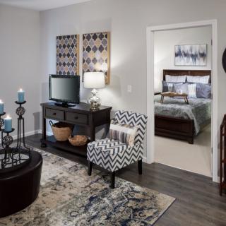 A stylish living room with a view into a cozy bedroom, featuring modern furniture and decor.
