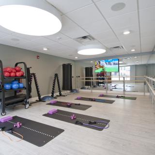 A modern fitness studio equipped with yoga mats, exercise balls, and large mirrors.