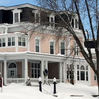 A large house in a snowy winter setting, surrounded by bare trees.