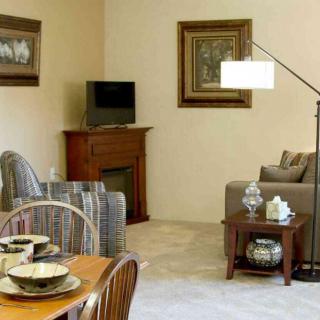 A cozy living room with a sofa, armchair, television, and a small dining area.