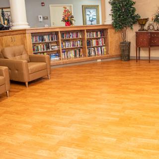 A welcoming interior space featuring a cozy sitting area, bookshelves, and wooden flooring.
