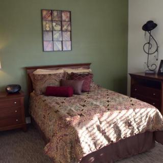 A cozy bedroom with a green accent wall and neatly arranged furniture.
