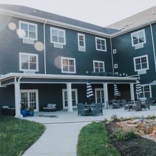 A modern residential building with outdoor patio seating and landscaped surroundings.