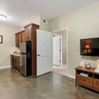 A modern apartment with a compact kitchen and living area featuring wood cabinetry and concrete flooring.