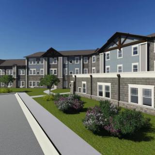 A modern residential apartment building with landscaped surroundings under a clear blue sky.