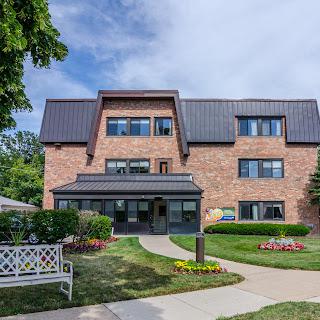 A charming residential building featuring modern architecture, set against a landscaped garden.