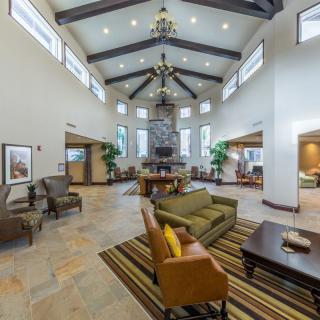 A spacious and modern lobby with high ceilings, elegant chandeliers, and comfortable seating arrangements surrounding a central fireplace.