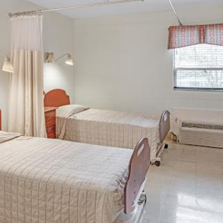 A clean and well-lit hospital room featuring two beds, designed for patient comfort.