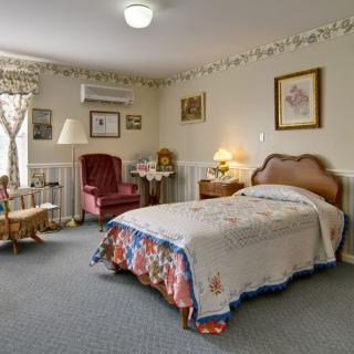 A cozy, vintage-style bedroom with a single bed, armchair, and decorative elements.