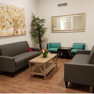 A modern living room with grey sofas, teal chairs, a wooden coffee table, and decorative elements like a large mirror and artwork.