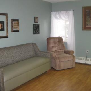 A cozy living room with a sofa, recliner, and decorated walls.