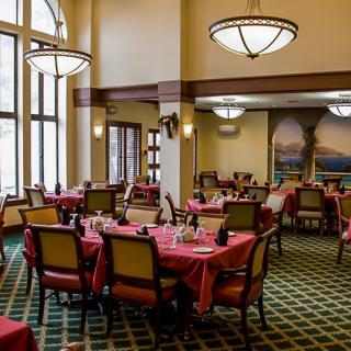 A spacious restaurant dining area with neatly arranged tables and elegant chandeliers.