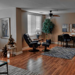 A cozy living room featuring wooden flooring, stylish furniture, and a workspace.
