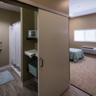 A modern interior featuring a bedroom and an adjacent bathroom with a sliding door.