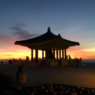 A silhouetted pavilion set against a vibrant sunset sky.
