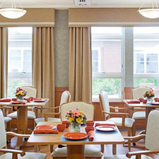 A cozy dining room with neatly arranged tables and colorful floral decorations.