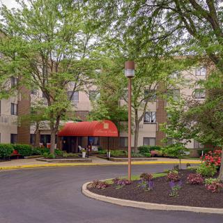 Entrance to an apartment complex with trees and landscaped driveway.