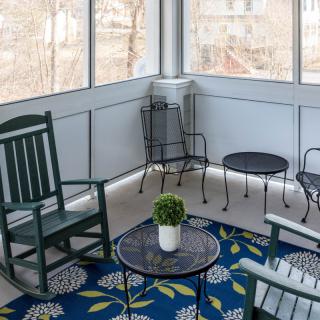 A cozy porch area with a rocking chair, small table, and decorative rug.