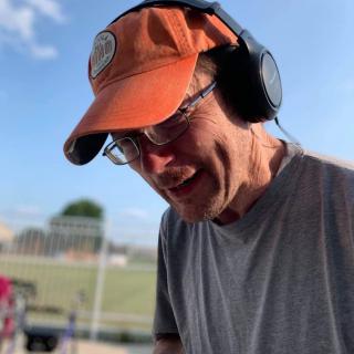 A man wearing an orange cap and headphones outdoors.