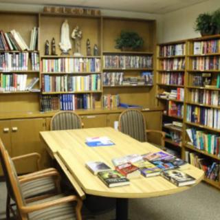 A cozy library room with bookshelves and a table surrounded by chairs.