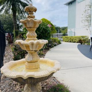 A decorative three-tiered fountain in a garden setting with a curving pathway.