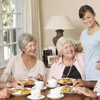 A group of seniors enjoying a meal together with a caregiver.