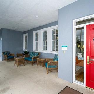 A welcoming porch with wicker chairs and a bright red door.