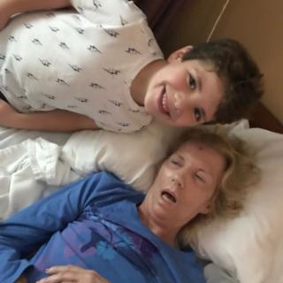 A child smiling next to an elderly person resting in bed.