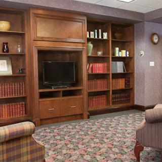 A cozy living room featuring a wooden bookshelf, a television, and comfortable seating.