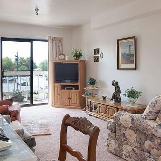 A cozy living room with vintage decor, featuring a floral sofa, television, and natural lighting.