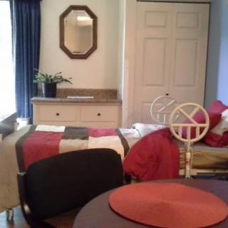 A cozy bedroom with a neatly made bed, dresser, mirror, and decor.