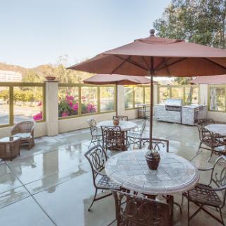 A serene outdoor patio area featuring a marble table and comfortable seating, perfect for enjoying the sunny weather.