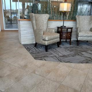 A cozy lobby area featuring stylish chairs, a small table, and a lamp, creating a welcoming atmosphere.