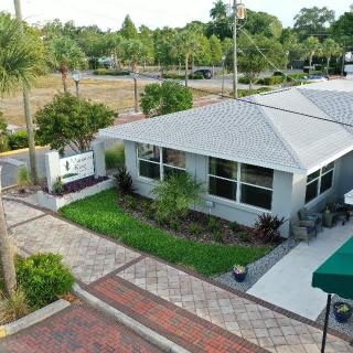 Aerial view of a house with a landscaped yard and surrounding pavement.