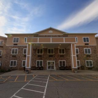 A hotel building with a stone facade and a prominent entrance, set against a partly cloudy sky.