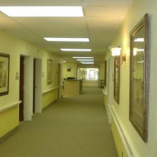 A well-lit hallway with artwork on the walls and multiple doors leading to rooms.