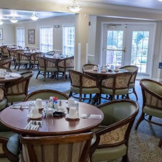 An elegant dining room with round tables and upholstered chairs, ready for guests.