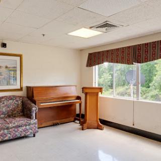 A cozy room featuring a piano, a sofa, and a window with natural light streaming in.