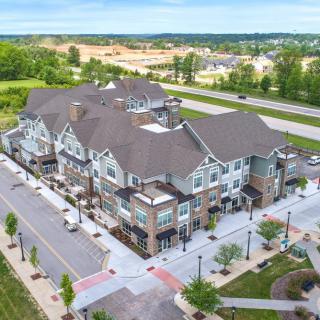 Aerial view of a mixed-use development with commercial and residential spaces surrounded by roads and greenery.
