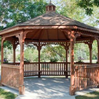 A wooden gazebo surrounded by trees in a park setting.