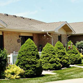 A well-maintained brick house with neatly trimmed shrubs in the front yard.