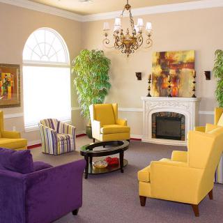 A vibrant and cozy living room featuring a mix of yellow and purple chairs, a fireplace, and elegant decor.