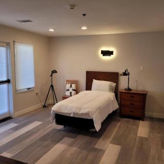 A modern, minimalist bedroom with a single bed and wooden flooring.