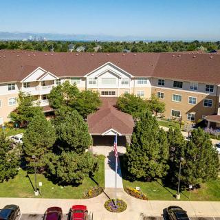 Aerial view of a residential building with surrounding trees and parking area.