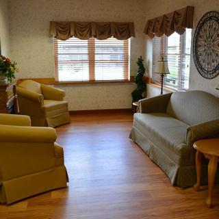 A cozy living room with a sofa, armchairs, and wooden flooring.