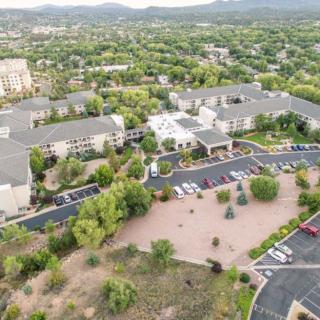 Aerial view of a suburban area with buildings surrounded by trees and parking lots.