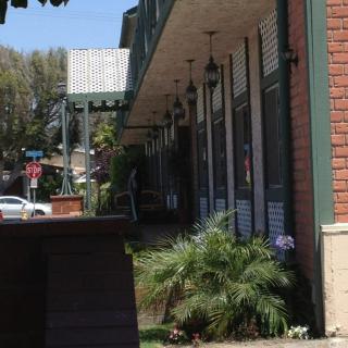 A street view of a building with plants and outdoor lights on a sunny day.