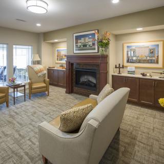 A cozy living room with a sofa facing a fireplace, complemented by elegant artwork and warm lighting.