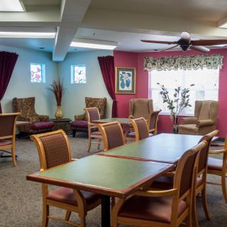 A well-decorated dining and sitting area with wooden tables and chairs, featuring colorful walls and curtains.