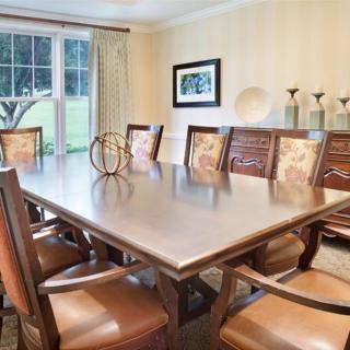 A spacious dining room with a large table and elegant chairs, complemented by tasteful decor and natural lighting from a window.